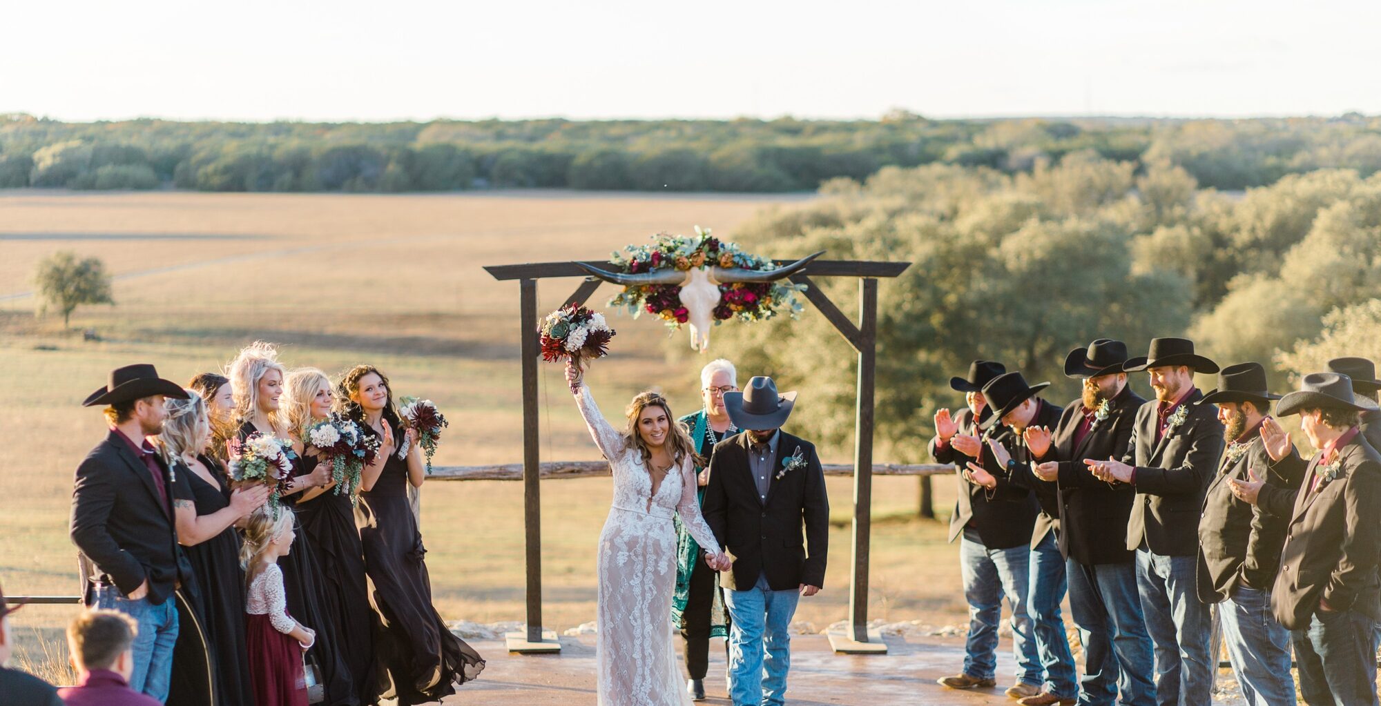 Wedding party in cowboy hats celebrating the recessional at golden hour
